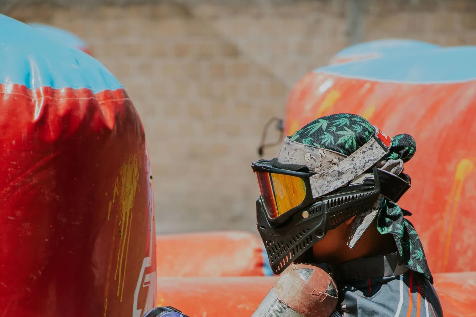 Joueur de paintball à genoux derrière un obstacle gonflable, masque et lanceur à trémie