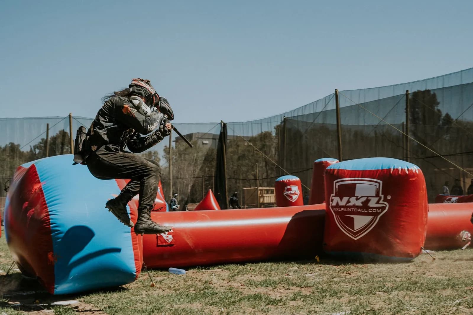 Joueur de paintball sautant par-dessus un obstacle gonflable pendant un match