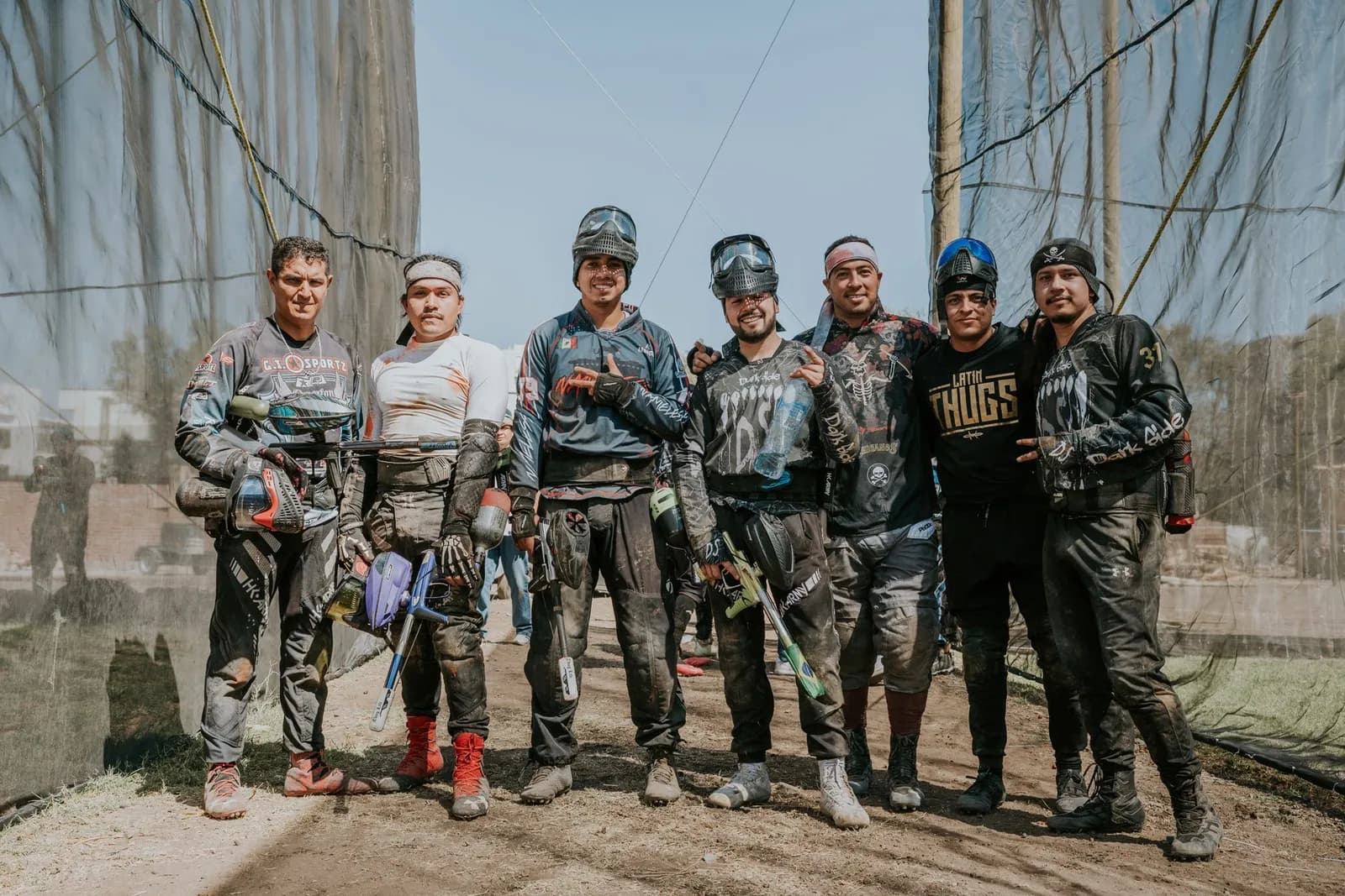 Groupe de joueurs de paintball souriants posant en tenue sur un terrain