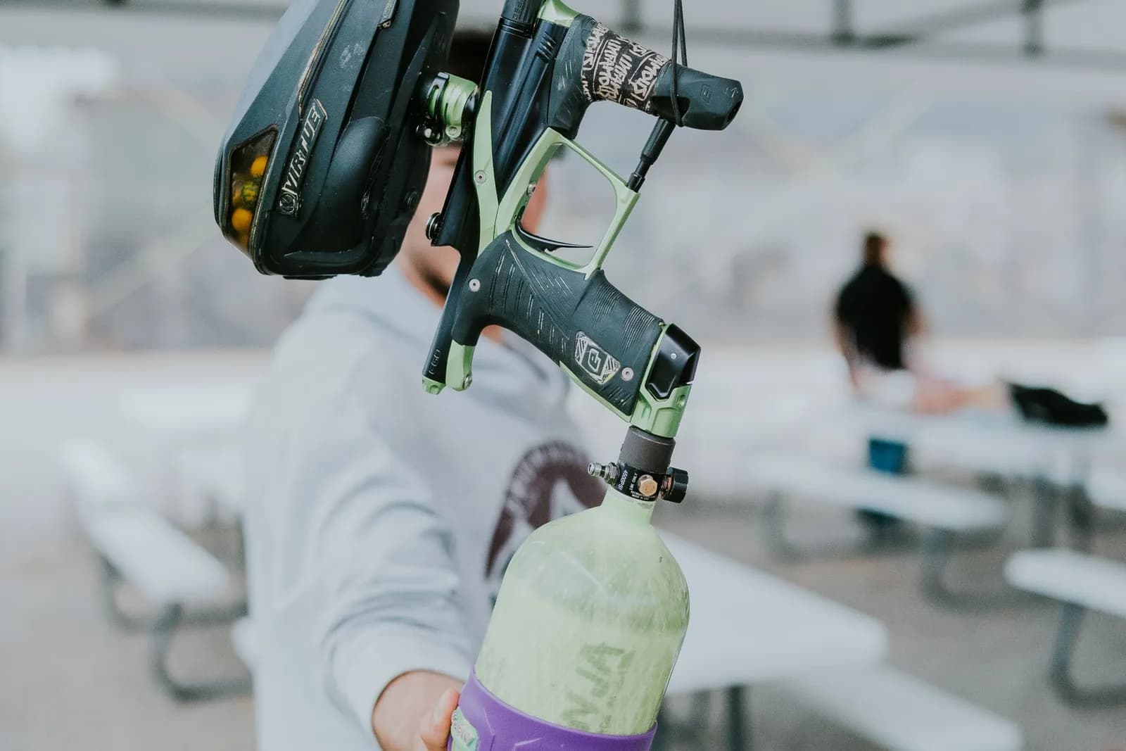 Joueur de paintball tenant un lanceur équipé d'une trémie noire et d'une bouteille d'air