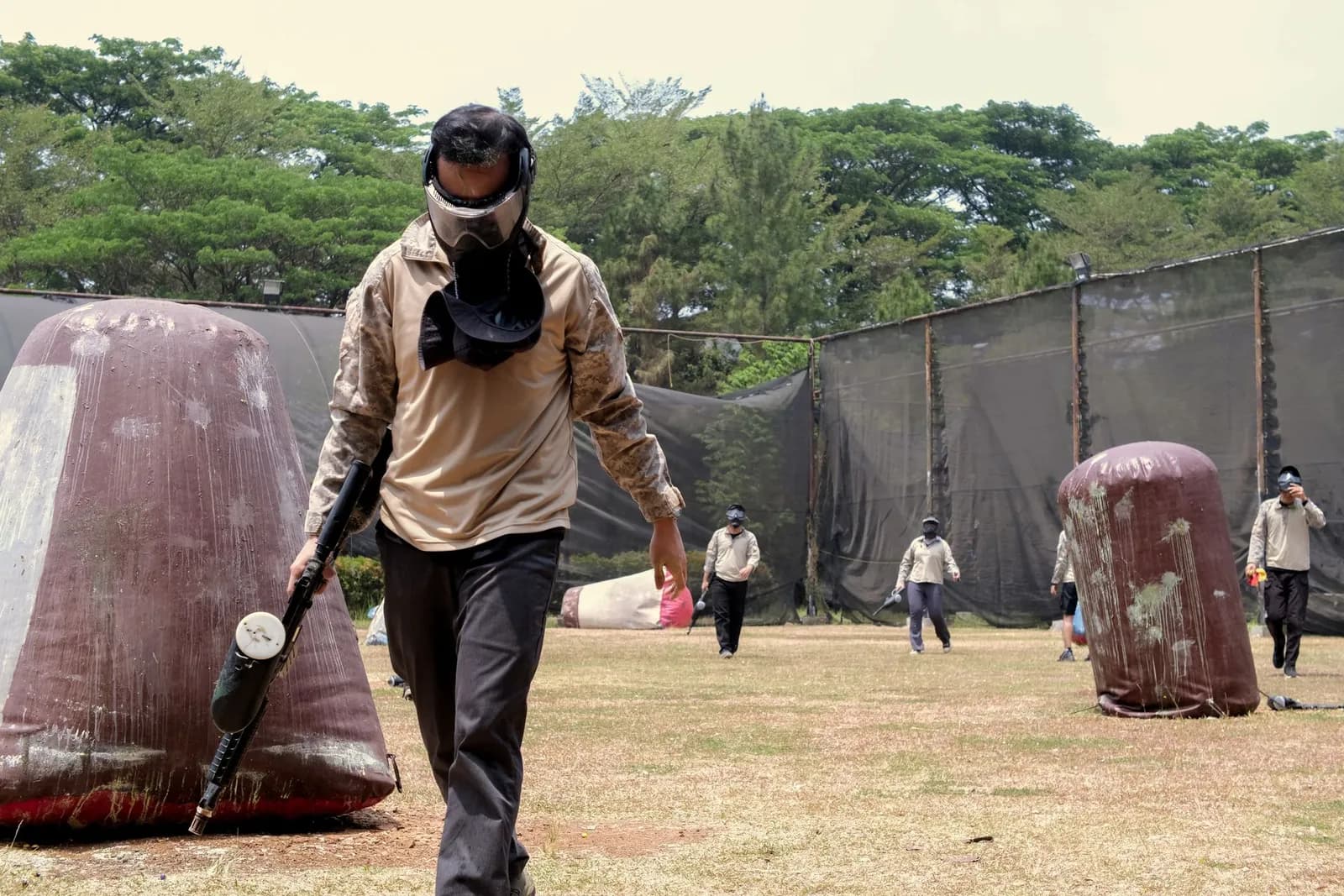 Joueur de paintball quittant le terrain, lanceur à la main, après son élimination