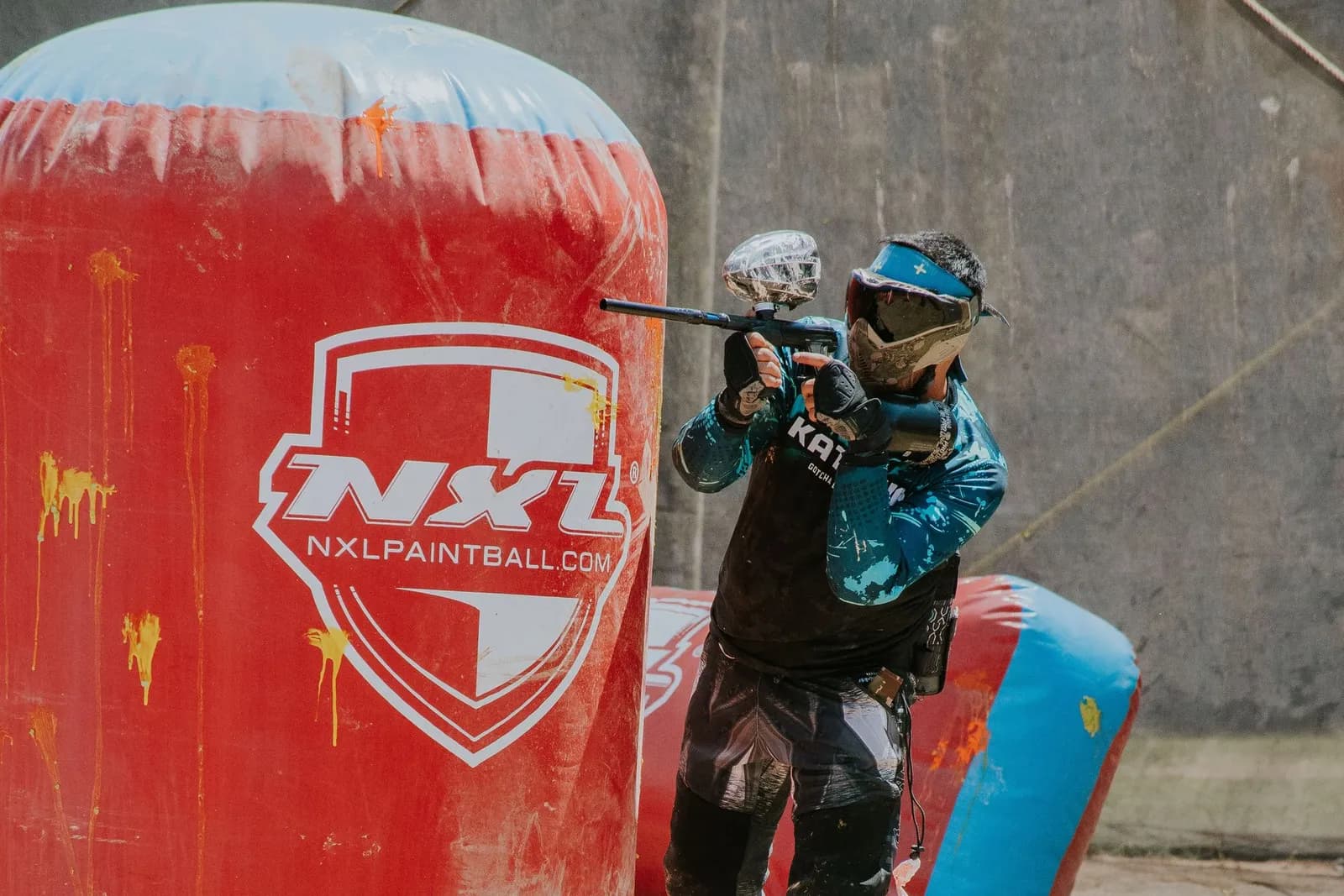 Joueur de paintball tirant à l'abri d'un obstacle gonflable rouge