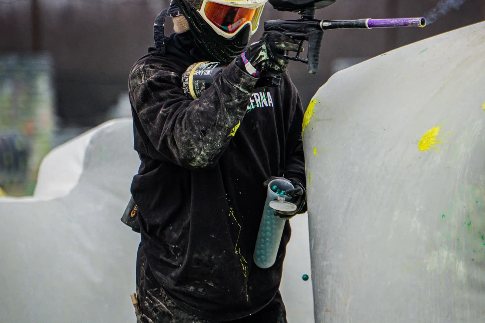Joueur de paintball masqué tirant derrière un obstacle gonflable avec un lanceur électronique