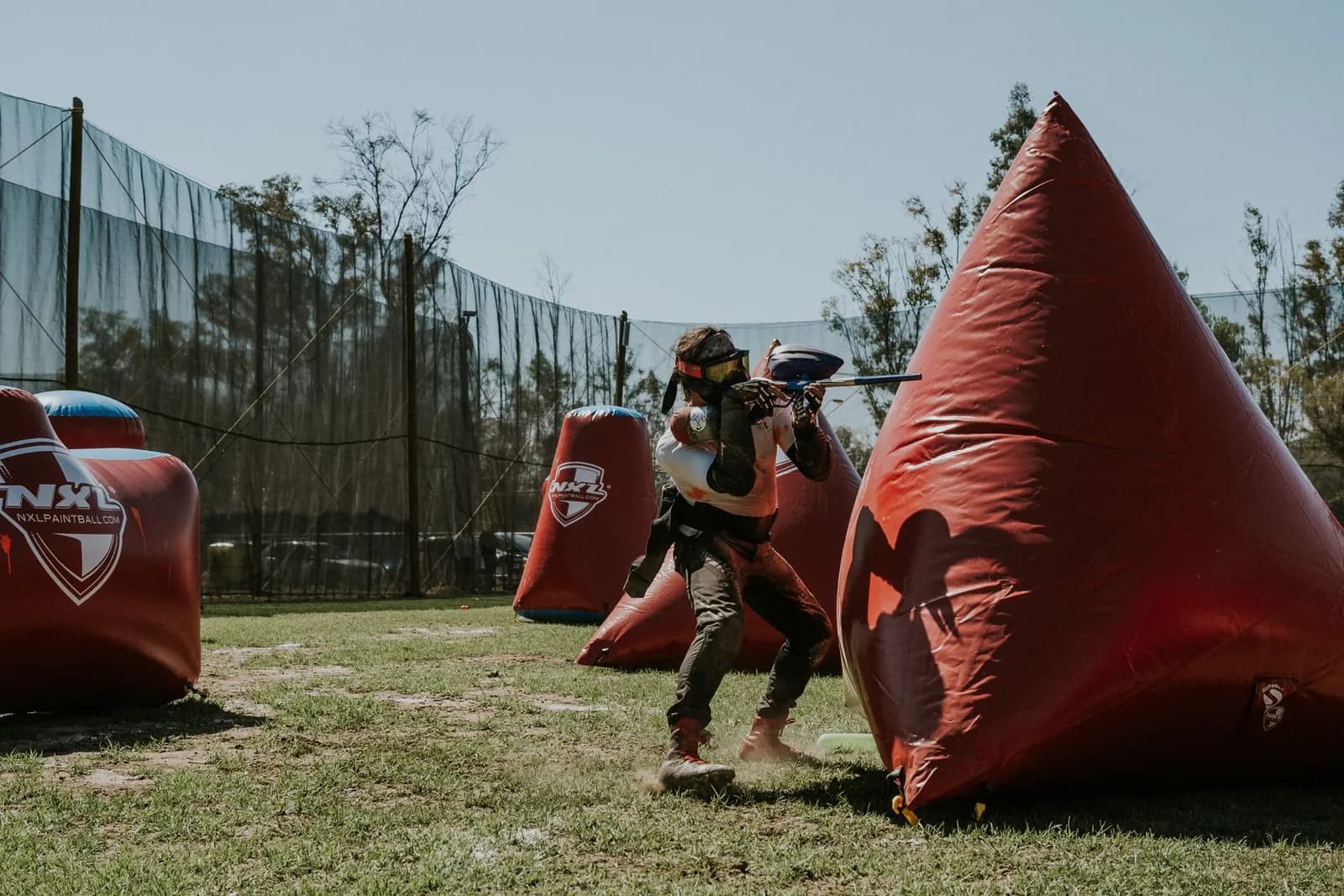 Joueur de paintball tirant à côté d'un obstacle gonflable sur un terrain de speedball