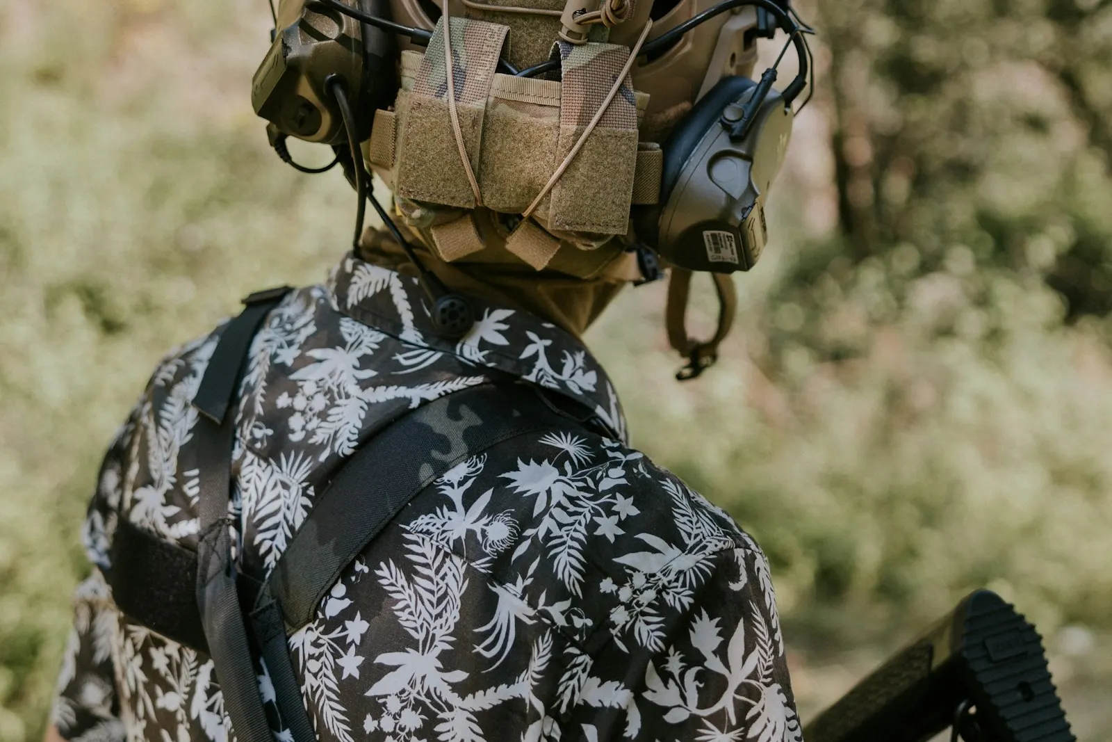Joueur d'airsoft vu de dos portant un casque équipé d'un casque audio et d'accessoires