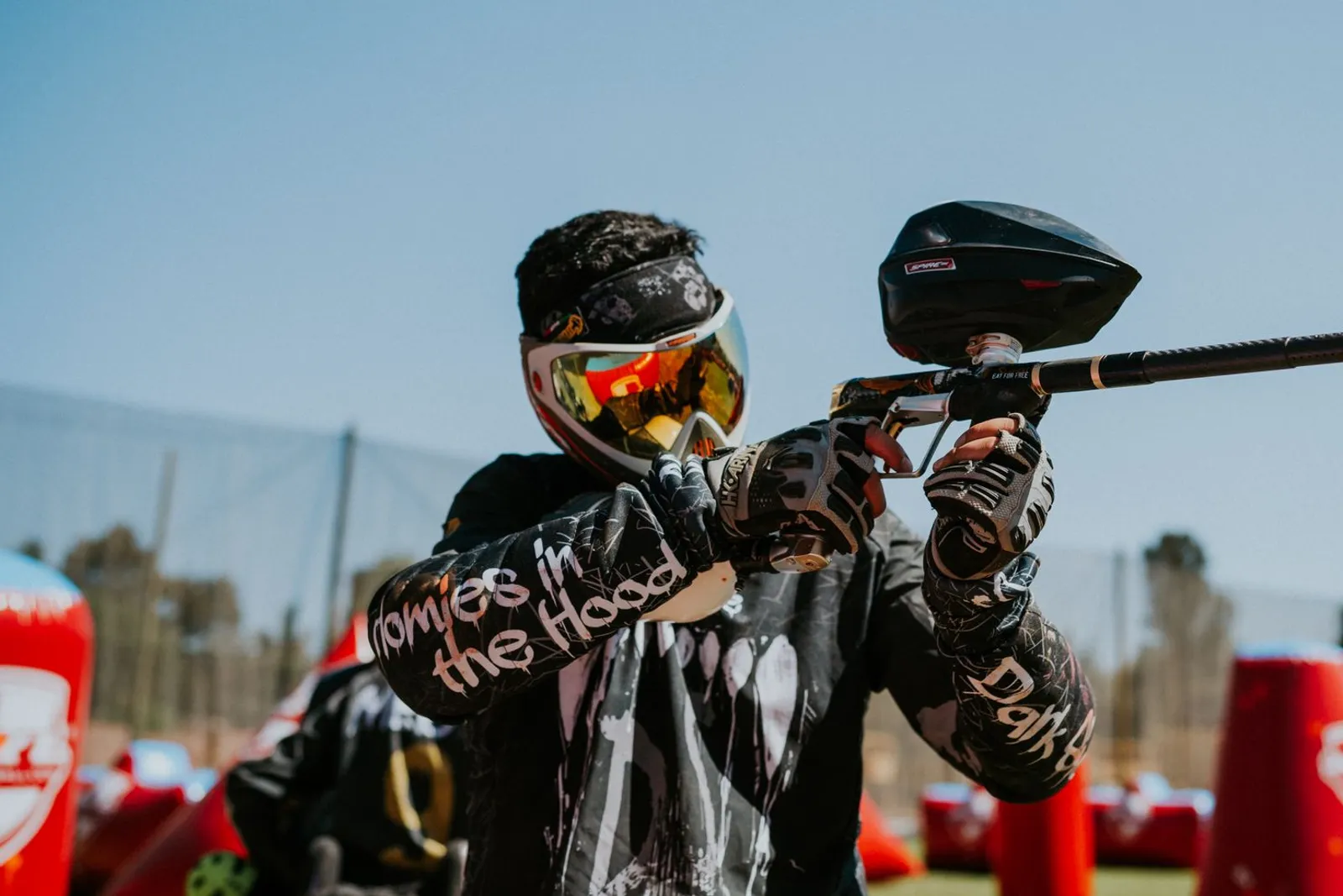 Joueur de paintball avec masque à écran miroir orangé visant avec son lanceur