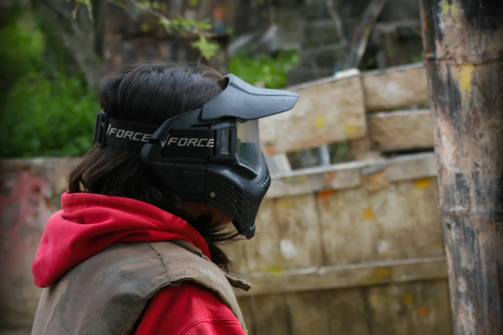 Jeune joueur de paintball en sweat rouge portant un masque, lanceur à la main