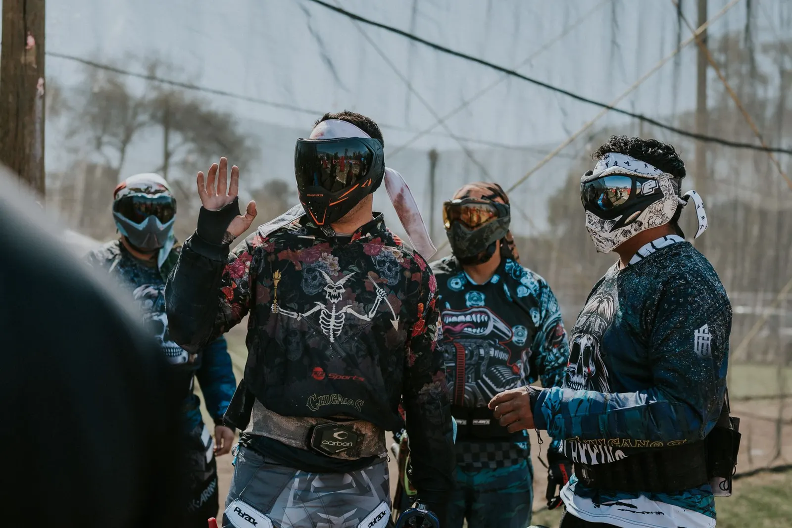 Groupe de joueurs de paintball masqués réunis autour de l'un d'eux qui explique une stratégie