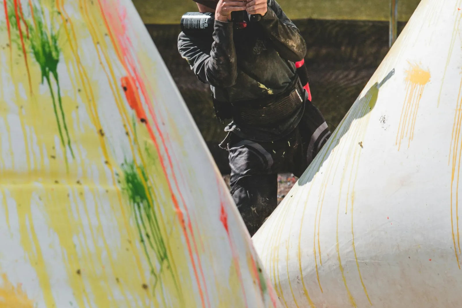 Joueur de paintball tirant entre deux obstacles gonflables couverts d'éclaboussures de peinture