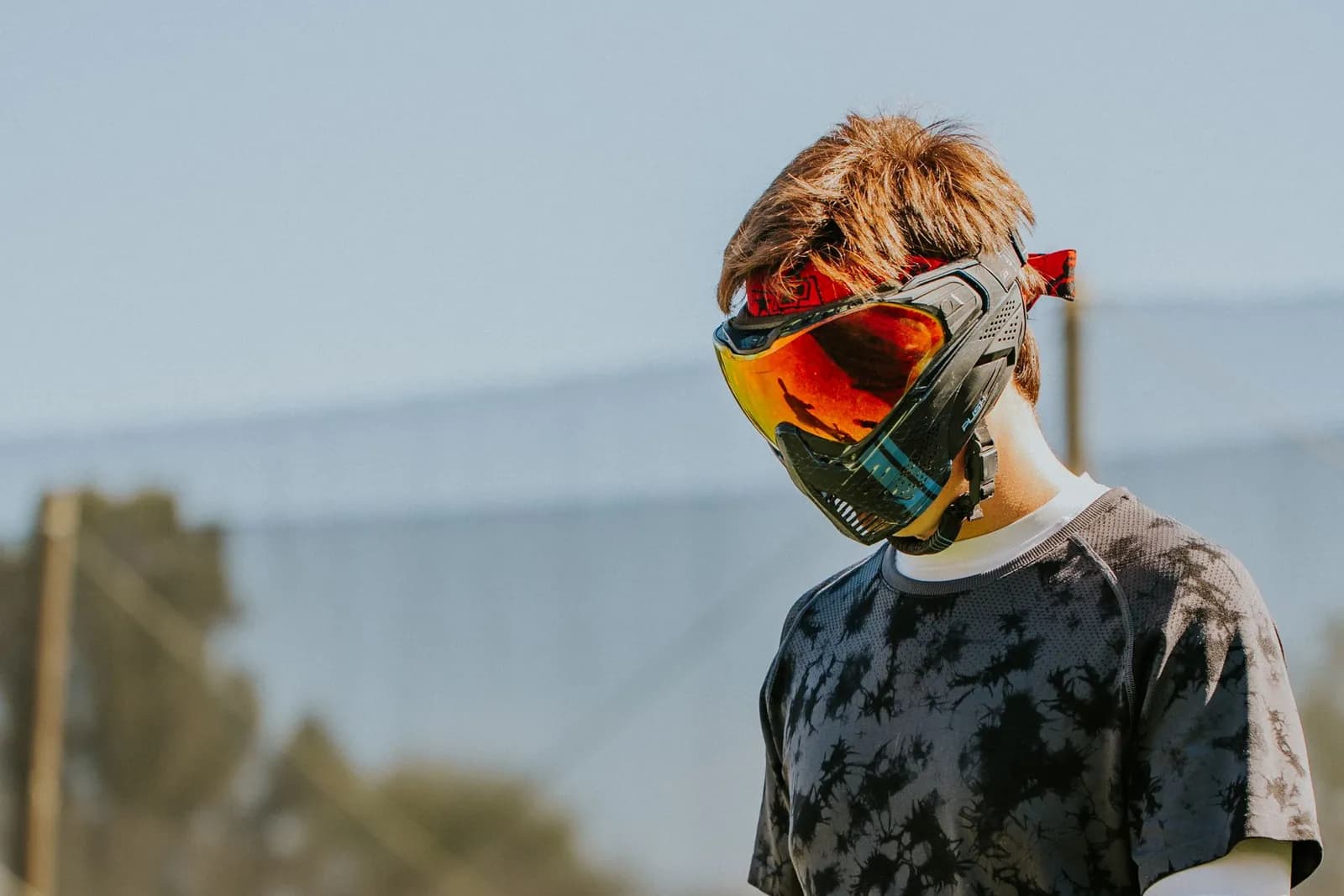 Jeune joueur de paintball portant un masque de protection à écran orangé sur un terrain