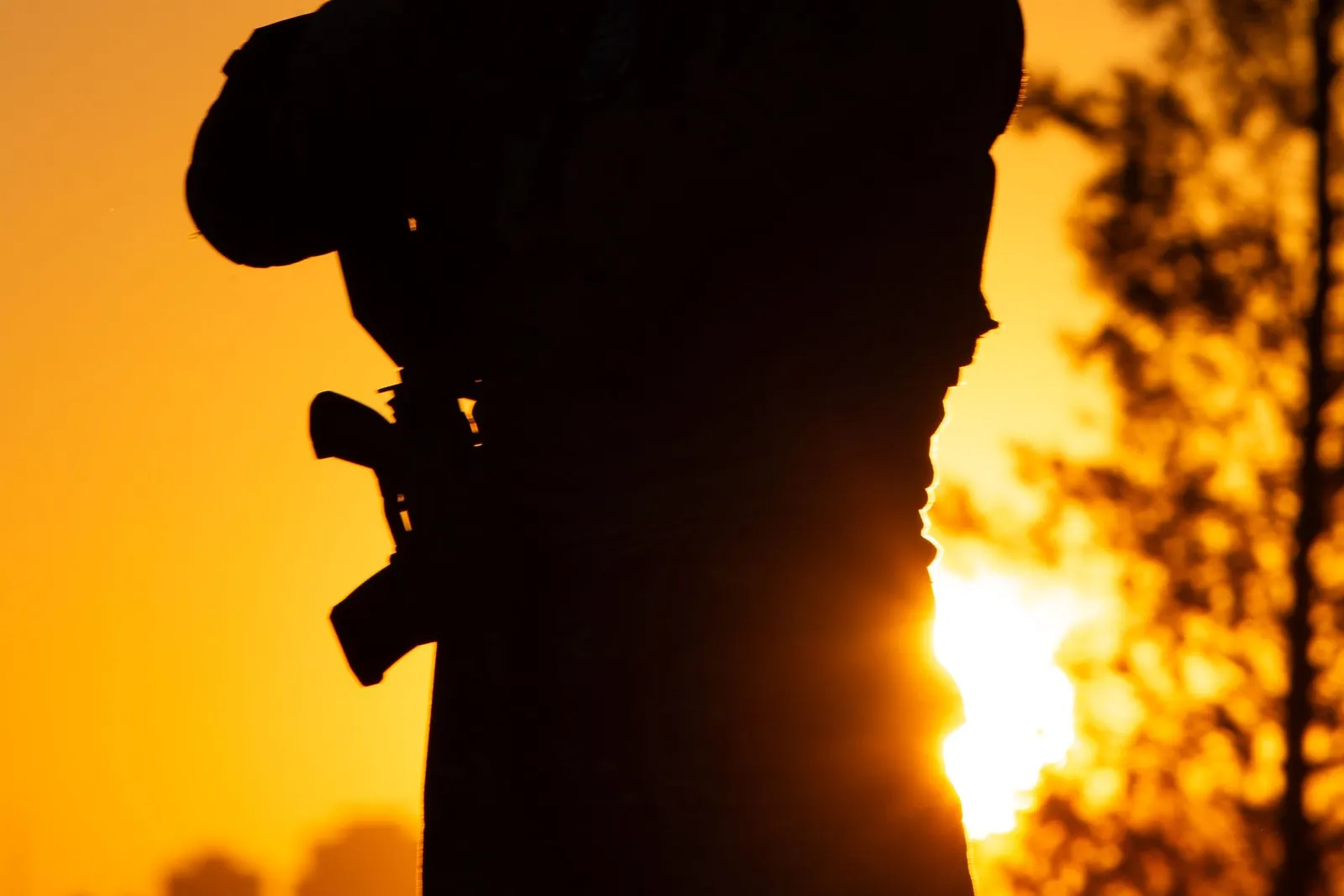 Silhouette d'un joueur de paintball se découpant sur un coucher de soleil orangé