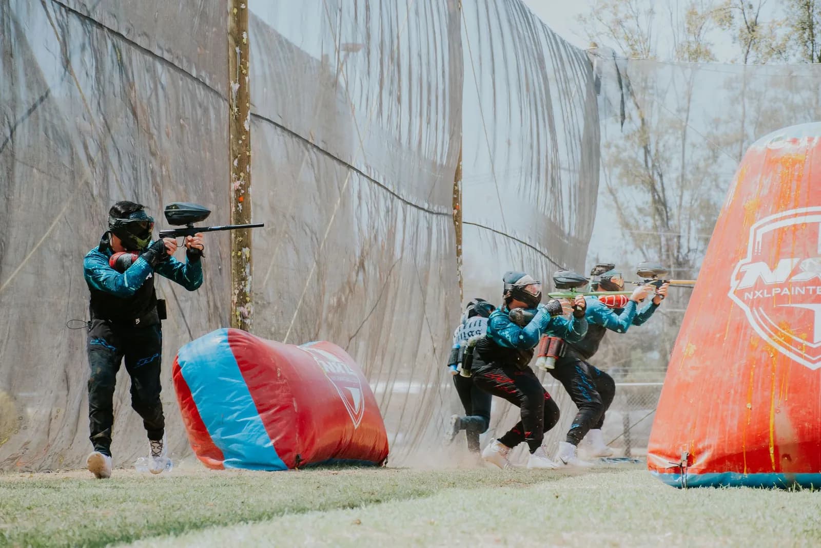 Équipe de joueurs de paintball avançant groupés derrière un obstacle gonflable