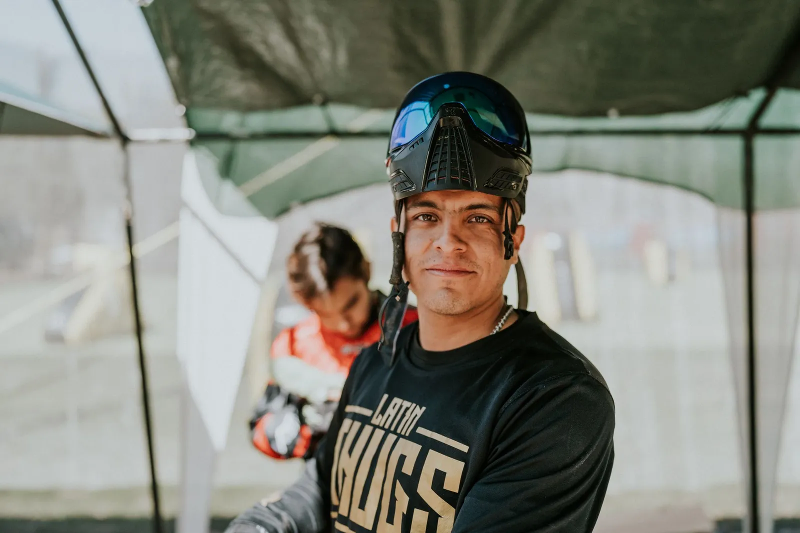 Joueur de paintball souriant dans la zone de sécurité, masque relevé sur le front