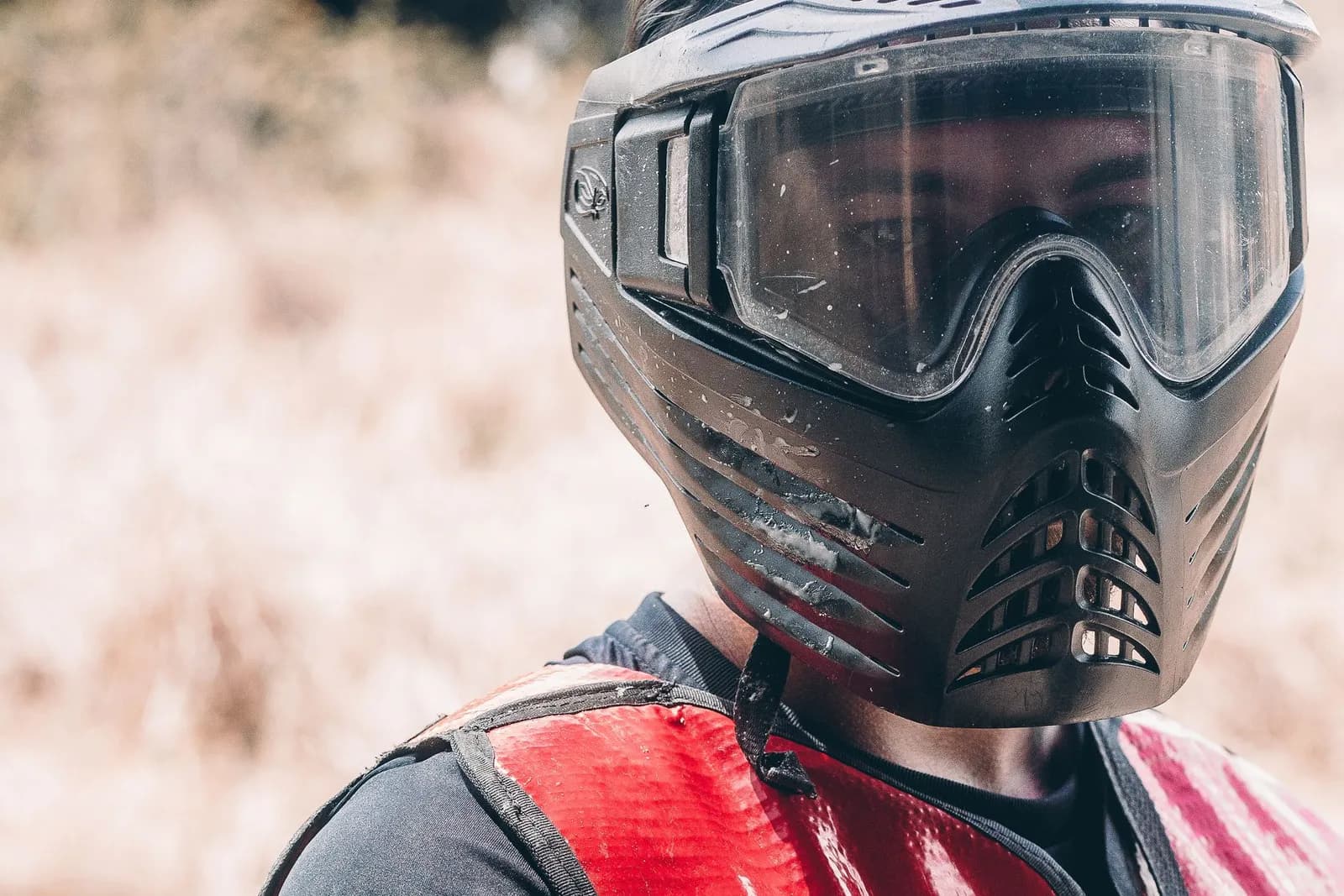 Joueur de paintball portant un masque intégral noir et une chasuble rouge