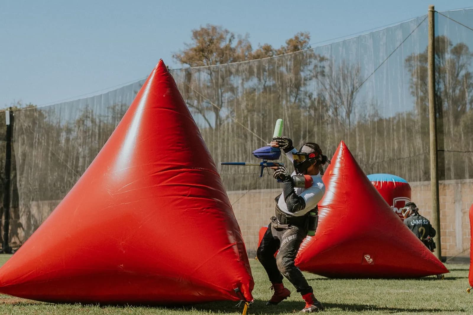 Joueur de paintball tirant à l'abri d'un obstacle gonflable rouge en forme de pyramide