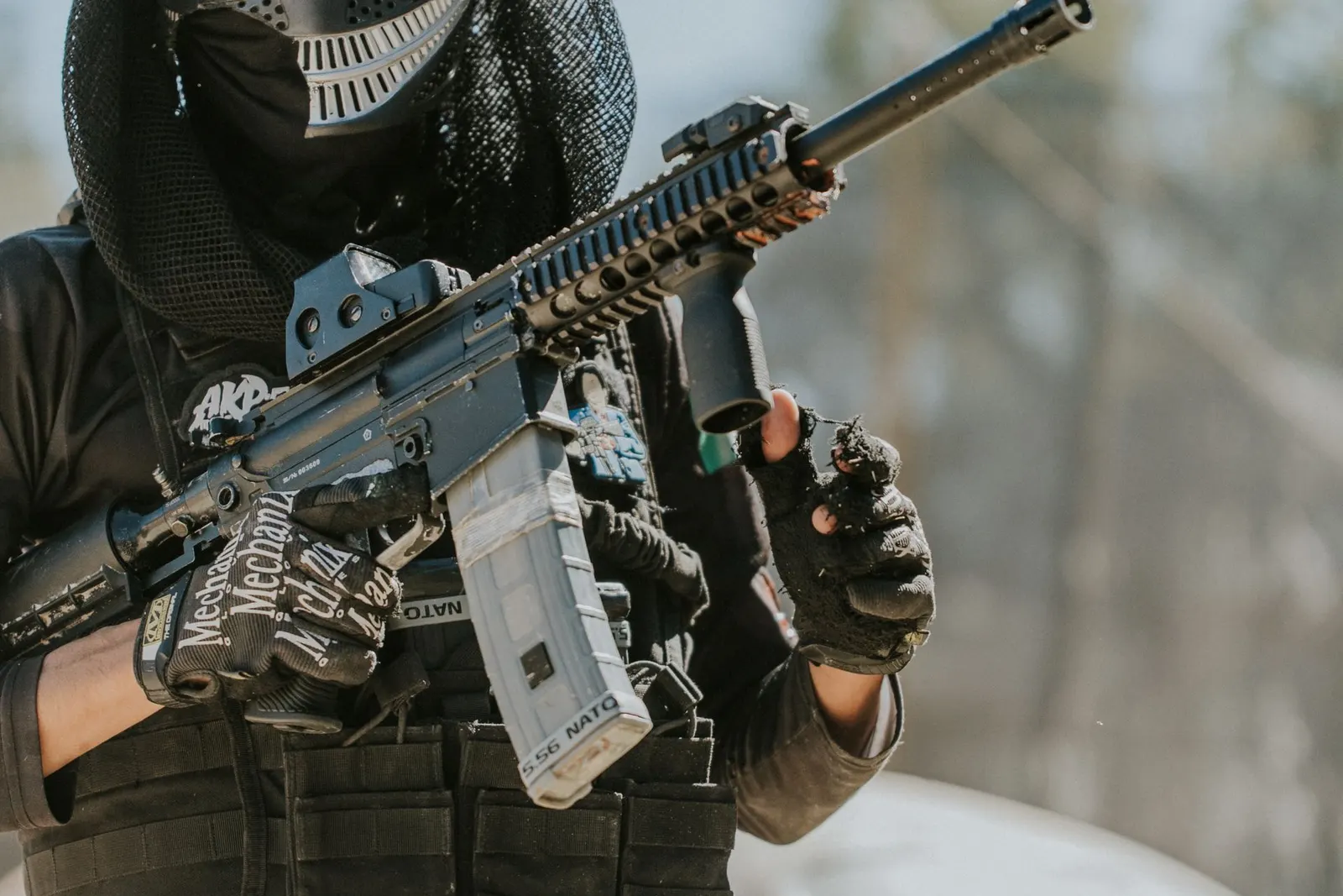 Joueur de paintball masqué tenant un lanceur à chargeur équipé d'un viseur