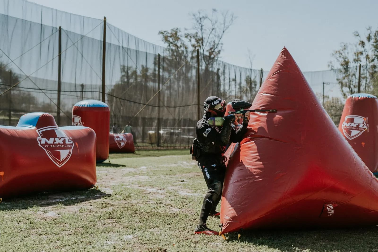 Joueur de speedball tirant à l'abri d'une pyramide gonflable rouge sur un terrain de compétition