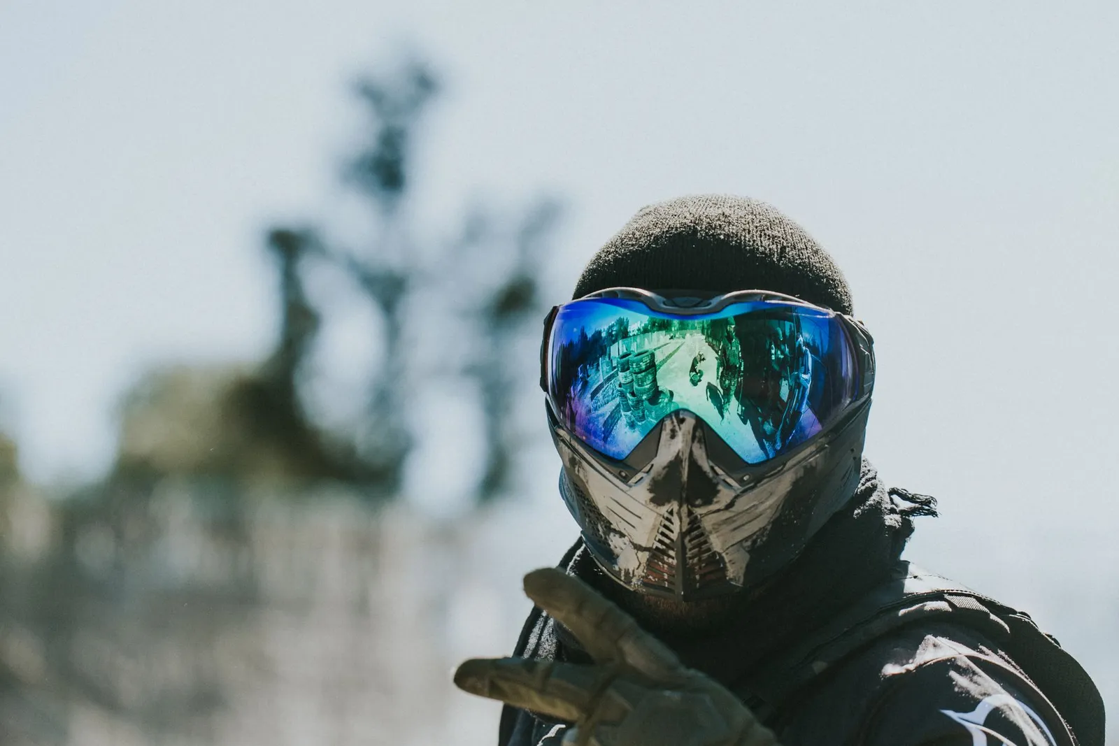 Joueur de paintball portant un masque à écran miroir et un gilet, faisant un signe vers l'objectif