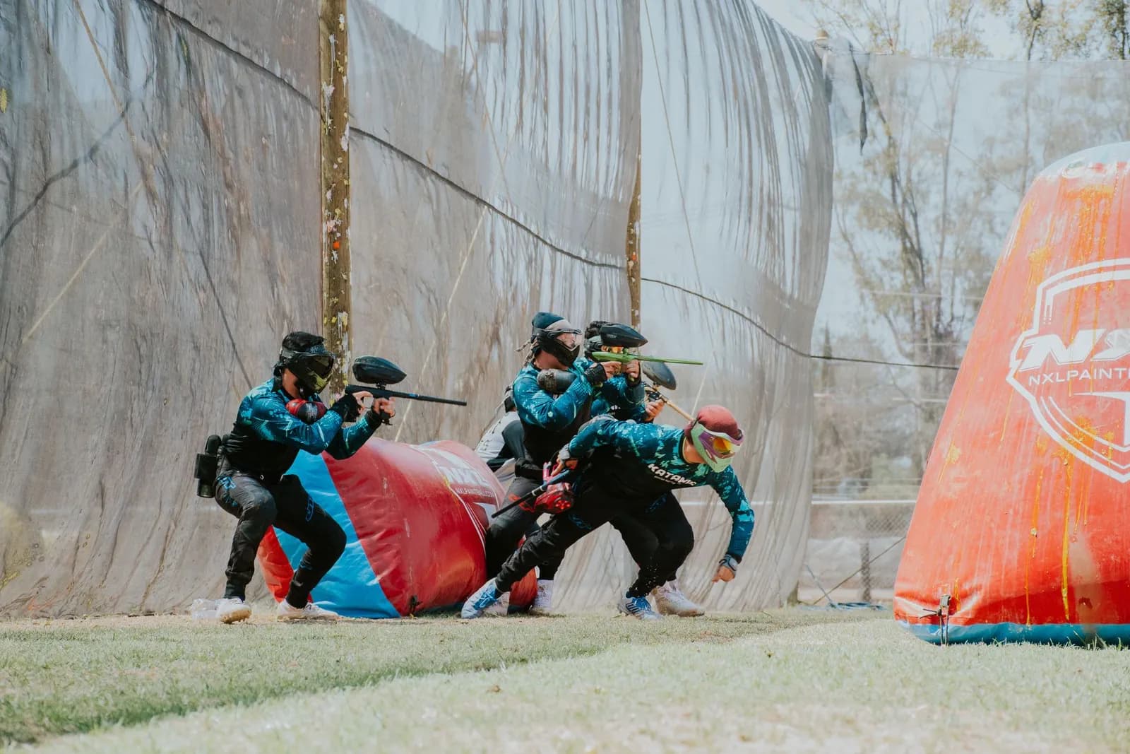 Joueurs de paintball en maillots assortis progressant groupés derrière un obstacle